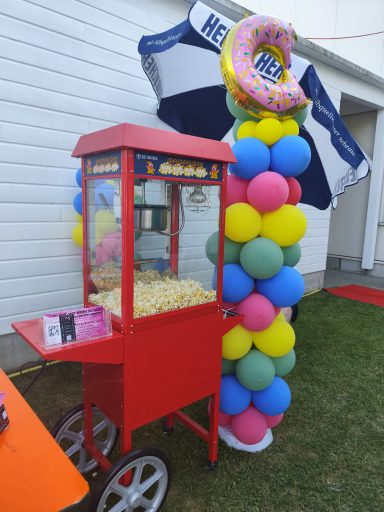 Event-Zuckerbäcker Popcornmaschine mieten Crailsheim Festlicher Popcorn-Stand mit dekorativer bunter Ballon-Umrandung für ein Open-Air Event.