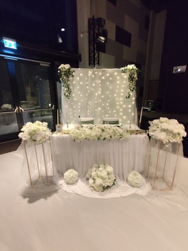 Hochzeitsdekoration Brauttisch Rems-Murr-Kreis Festlich dekorierter Brauttisch mit weiĂźem TĂĽll, Blumen und LED-Lichtervorhang fĂĽr eine Hochzeit.
