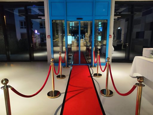 VIP Roter Teppich mieten Stuttgart Roter Teppich mit goldenen Absperrständern und roten Kordeln vor einer Event-Location.